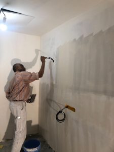 Léon est en train d'appliquer de l'enduit sur ce chantier de rénovation de bureau